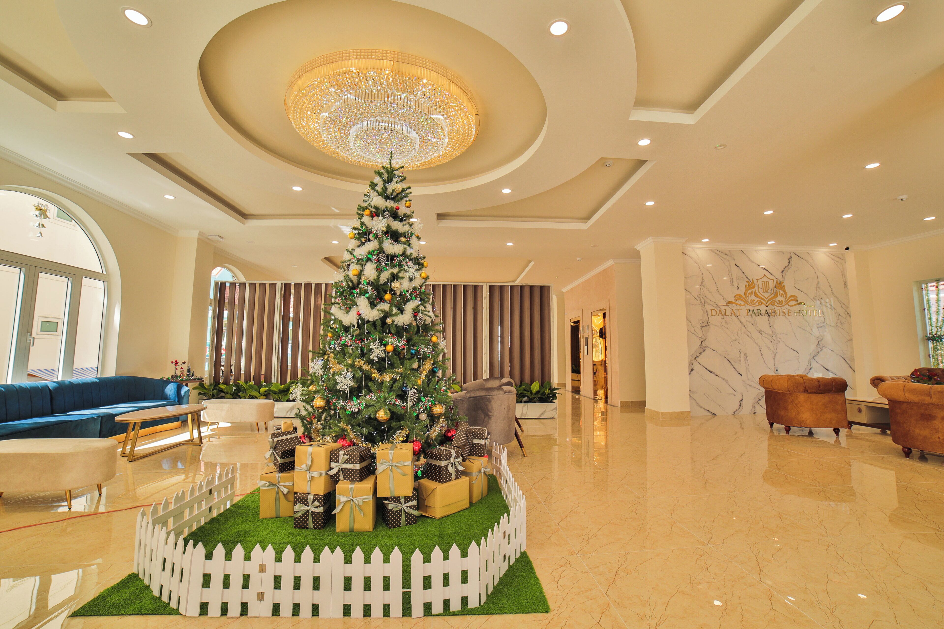 A lobby with a Christmas tree, plush seating, and a marble reception desk.