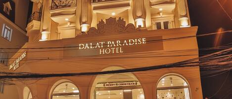 Das Hotel Dalat Paradise mit auffälligem Schild, mehreren Balkonen und einer Treppe zum Eingang.