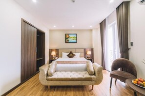 A hotel room with a bed, bedside lamps, a chair, a table with fruit, and a painting on the wall. - Dalat Paradise Hotel (Xuan Huong - Da Lat)