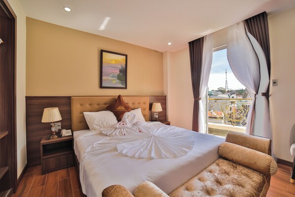 A hotel room with a large bed, a view of the Eiffel Tower, and a balcony with a railing. - Dalat Paradise Hotel (Xuan Huong - Da Lat)