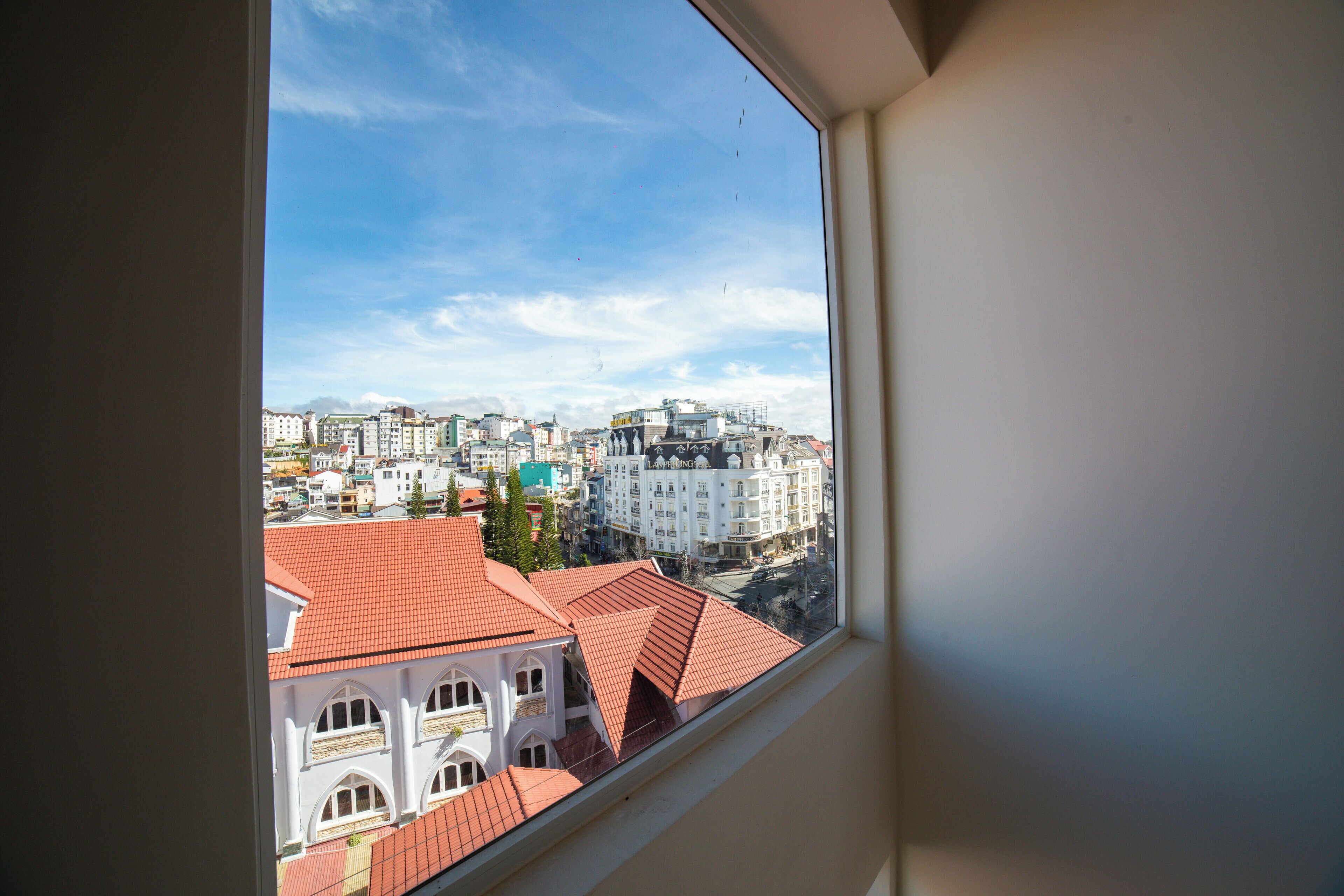 A view from a window overlooking a cityscape with buildings and a clear sky.