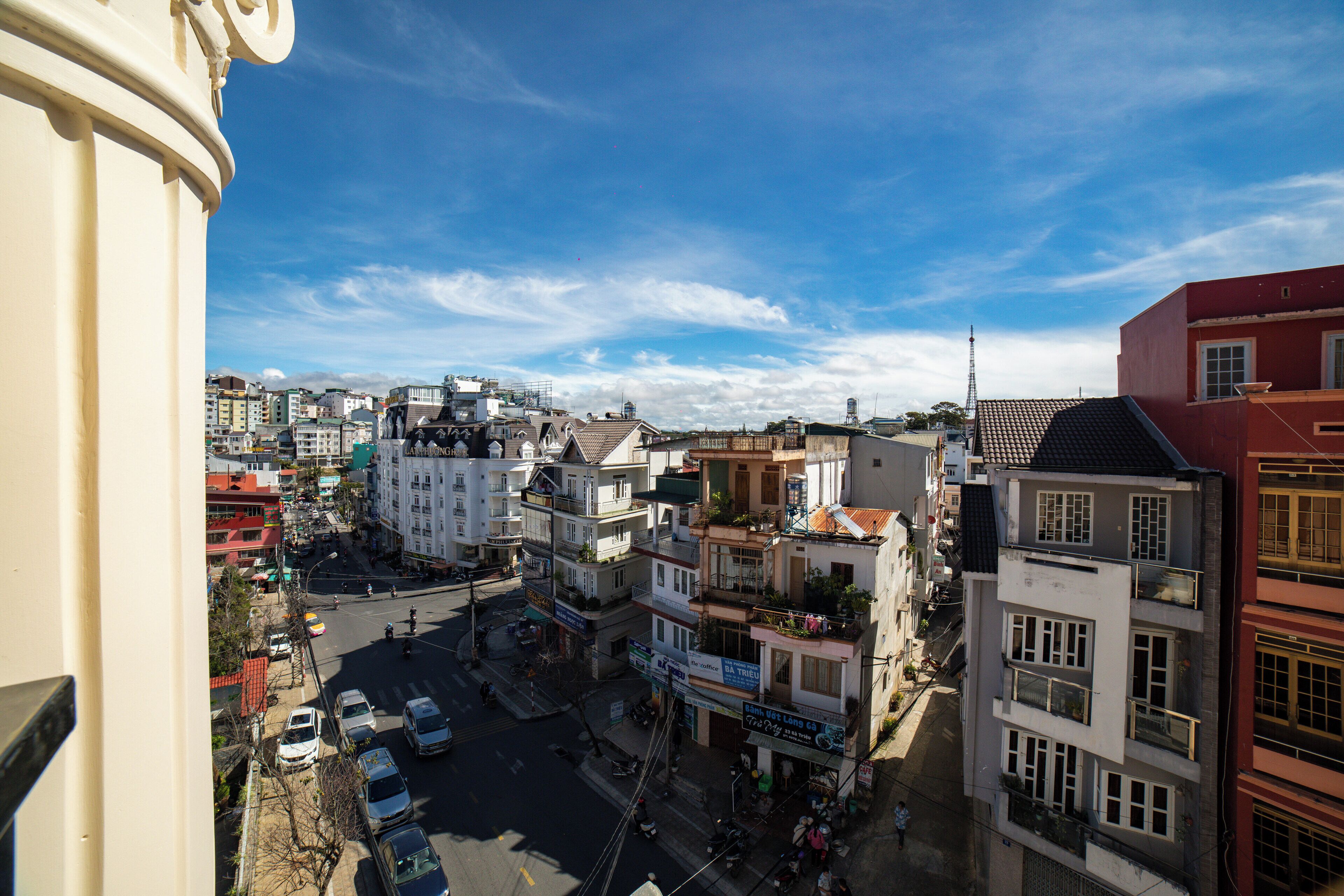 A cityscape with multi-story buildings, a busy street, and a clear sky.