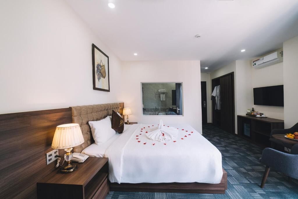Une chambre d’hôtel avec un lit bien fait, une table de chevet avec une lampe, un téléviseur et un petit coin salon.