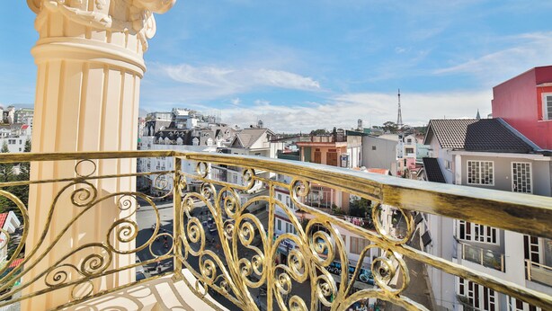 Un balcon doté de balustrades en métal ouvragé, donnant sur un paysage urbain composé de différents bâtiments.