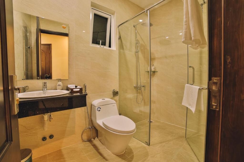 A modern bathroom with a glass-enclosed shower, a toilet, a sink, and a mirror.