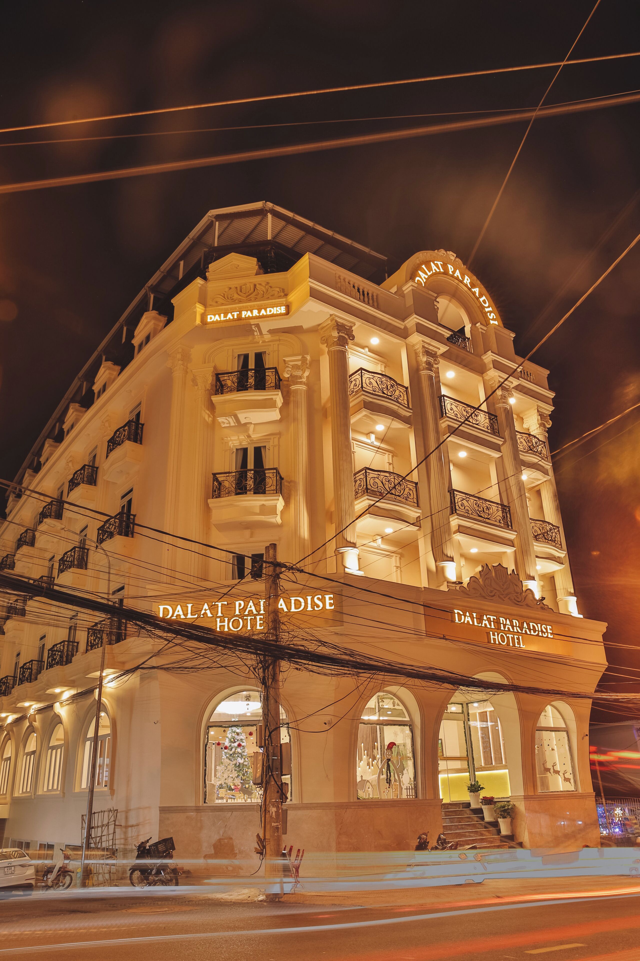 A multi-story hotel with balconies and arched windows, named "DALAT PARADISE HOTEL".