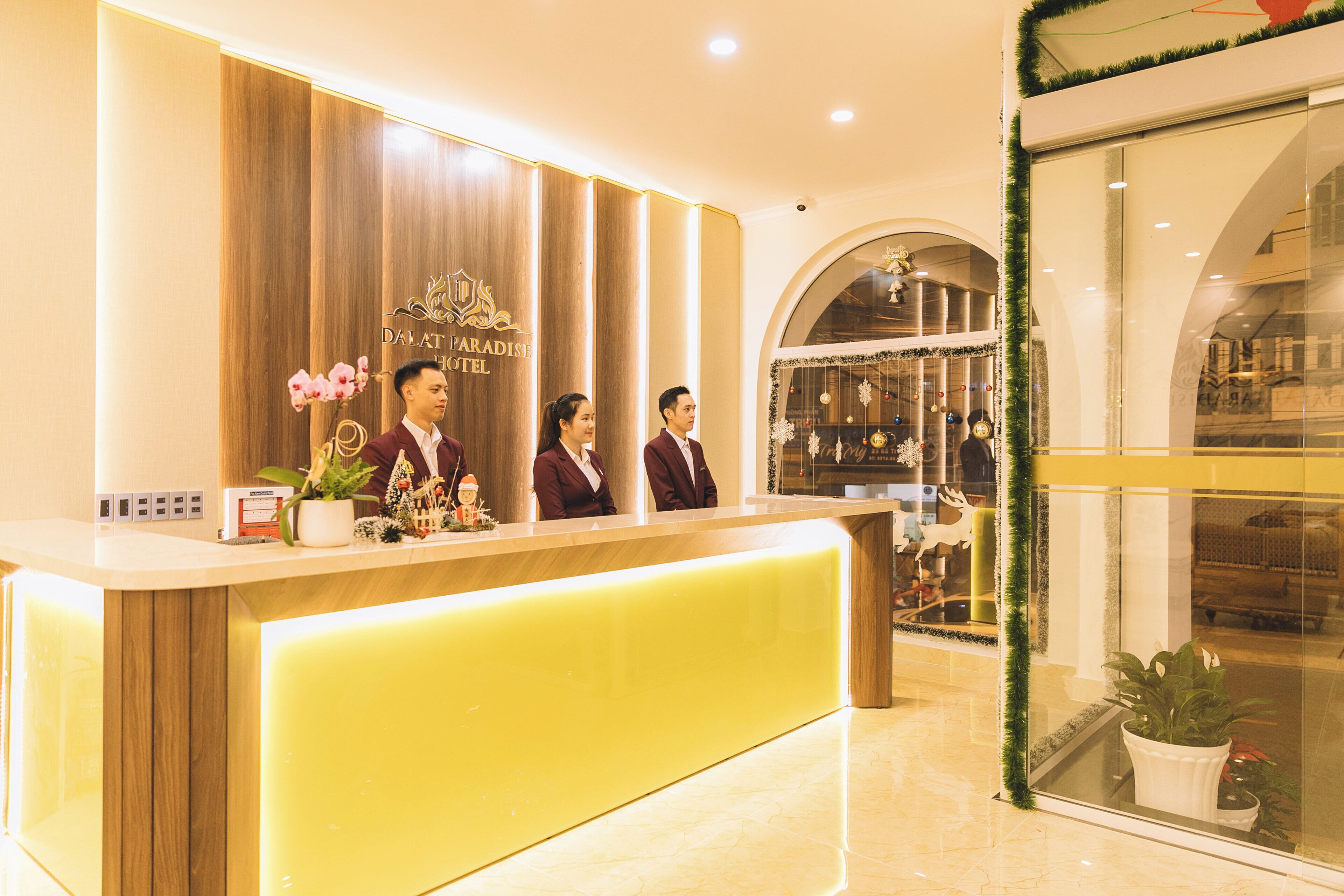 A hotel reception desk with a wooden panel design, a bright yellow counter, and a Christmas decoration.