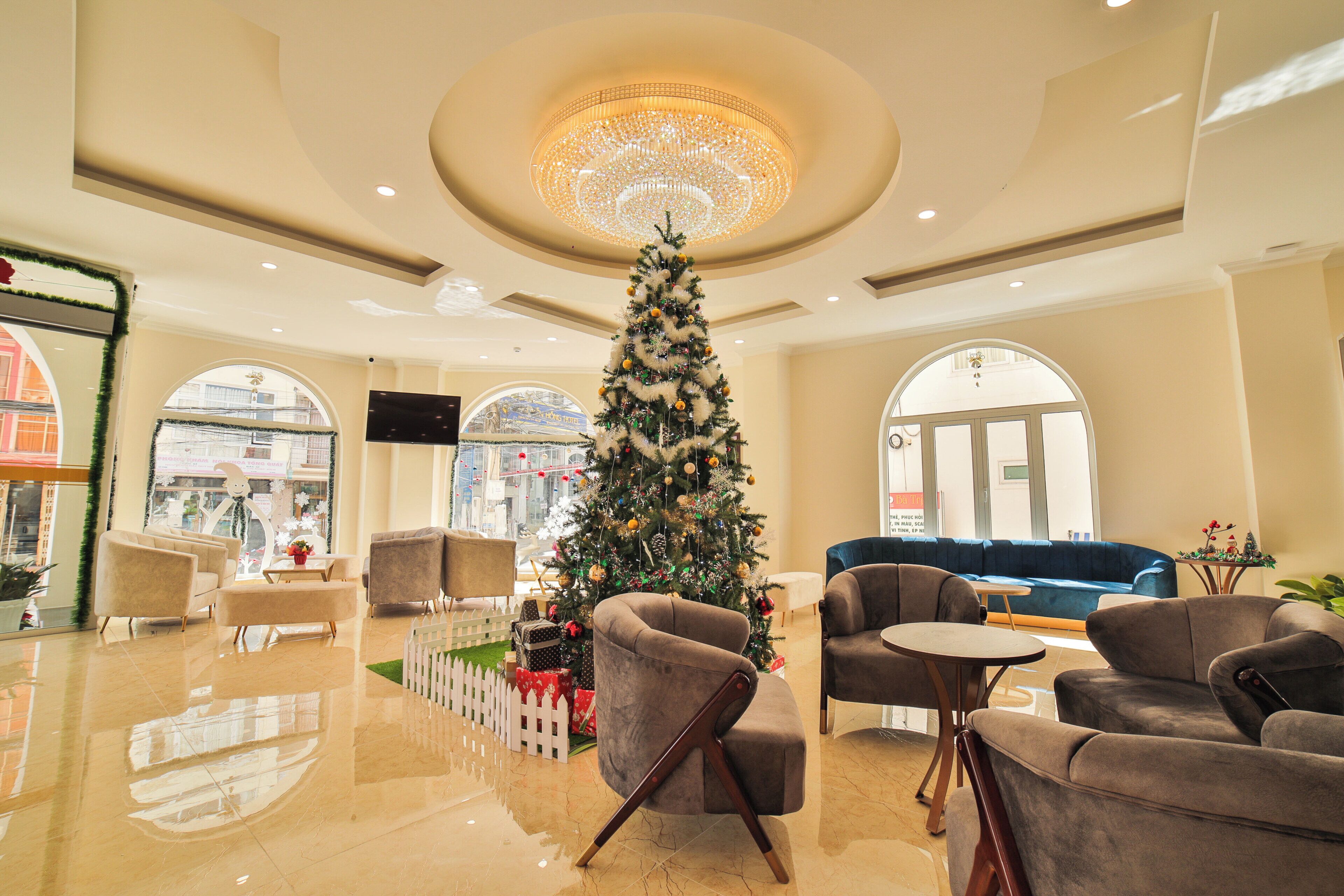 A spacious lobby with a large Christmas tree, comfortable seating, and a chandelier.
