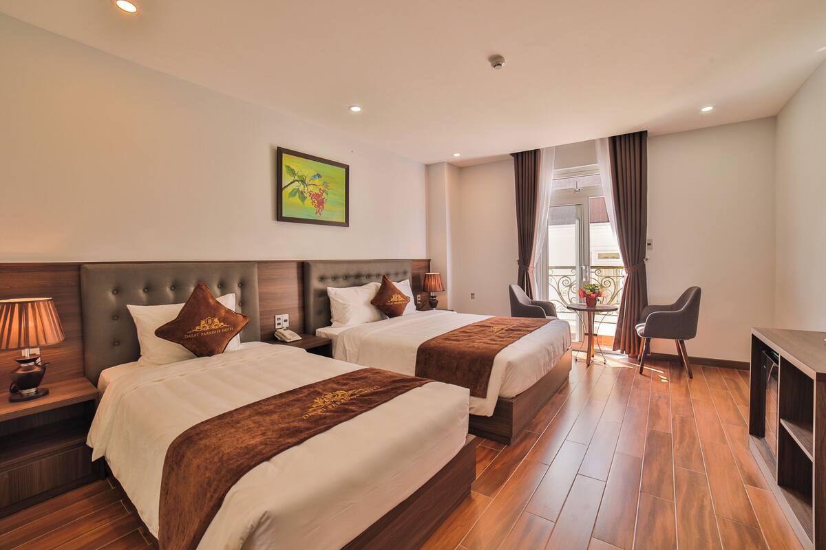 A hotel room with two beds, a desk, and a chair.