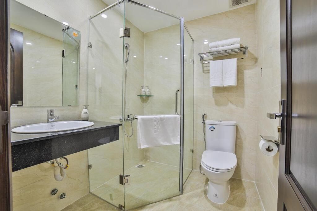A modern bathroom with a glass-enclosed shower, a sink, a toilet, and a towel rack.