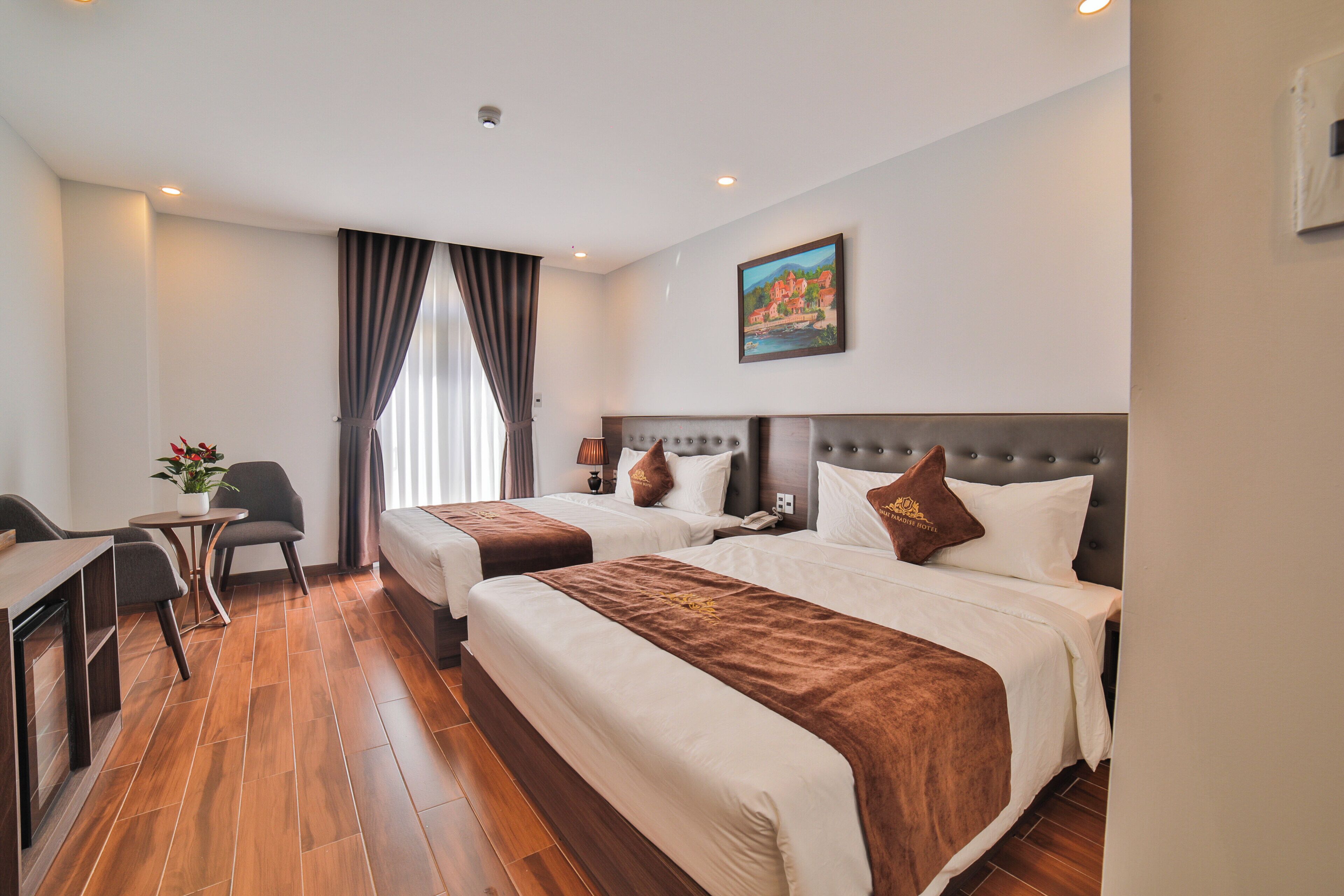 A hotel room with two beds, a desk, and a chair.