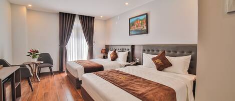 A hotel room with two beds, a desk, and a chair.