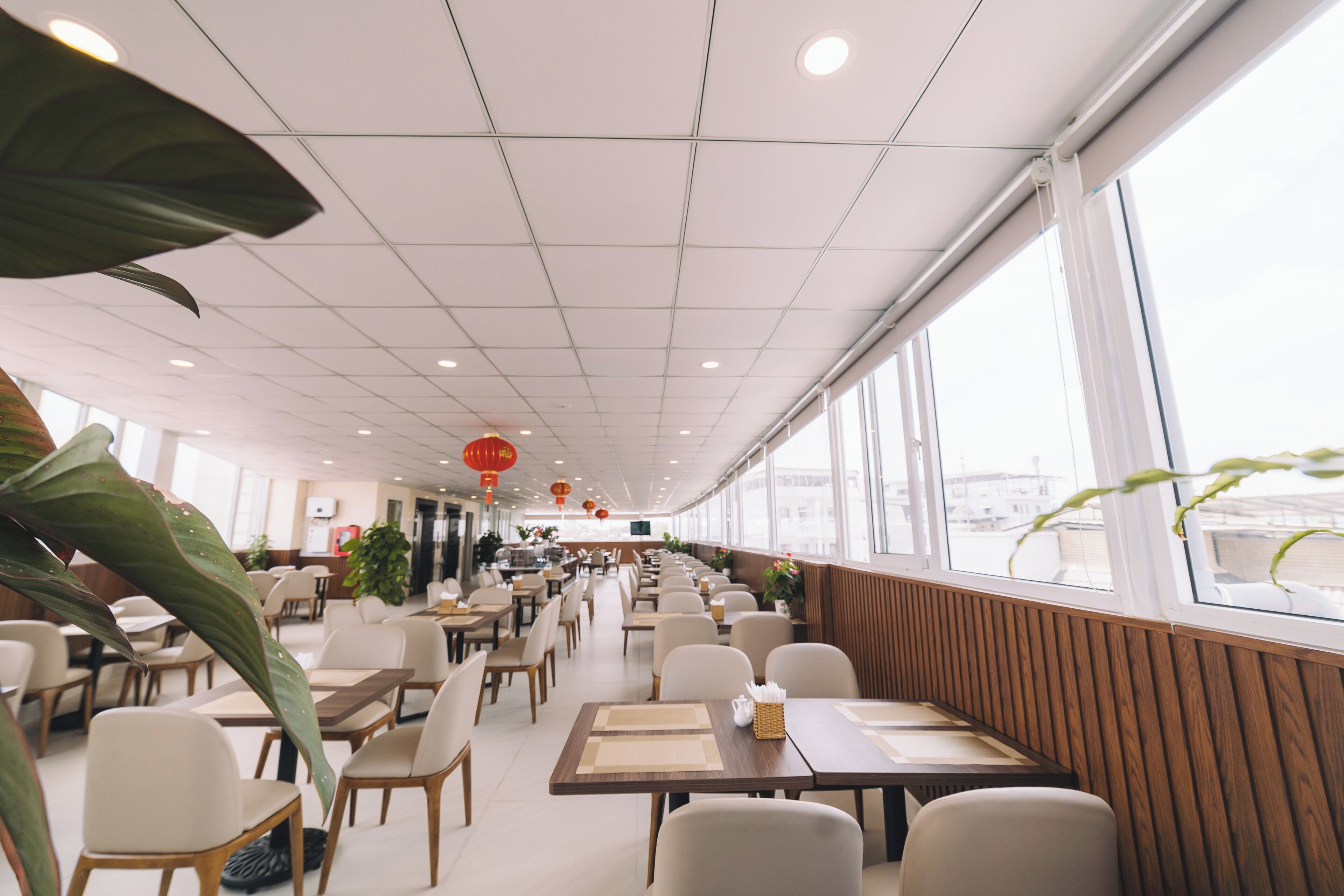 Ein geräumiges Restaurant mit hohen Decken, viel Platz und großen Fenstern mit Blick auf die Stadt.
