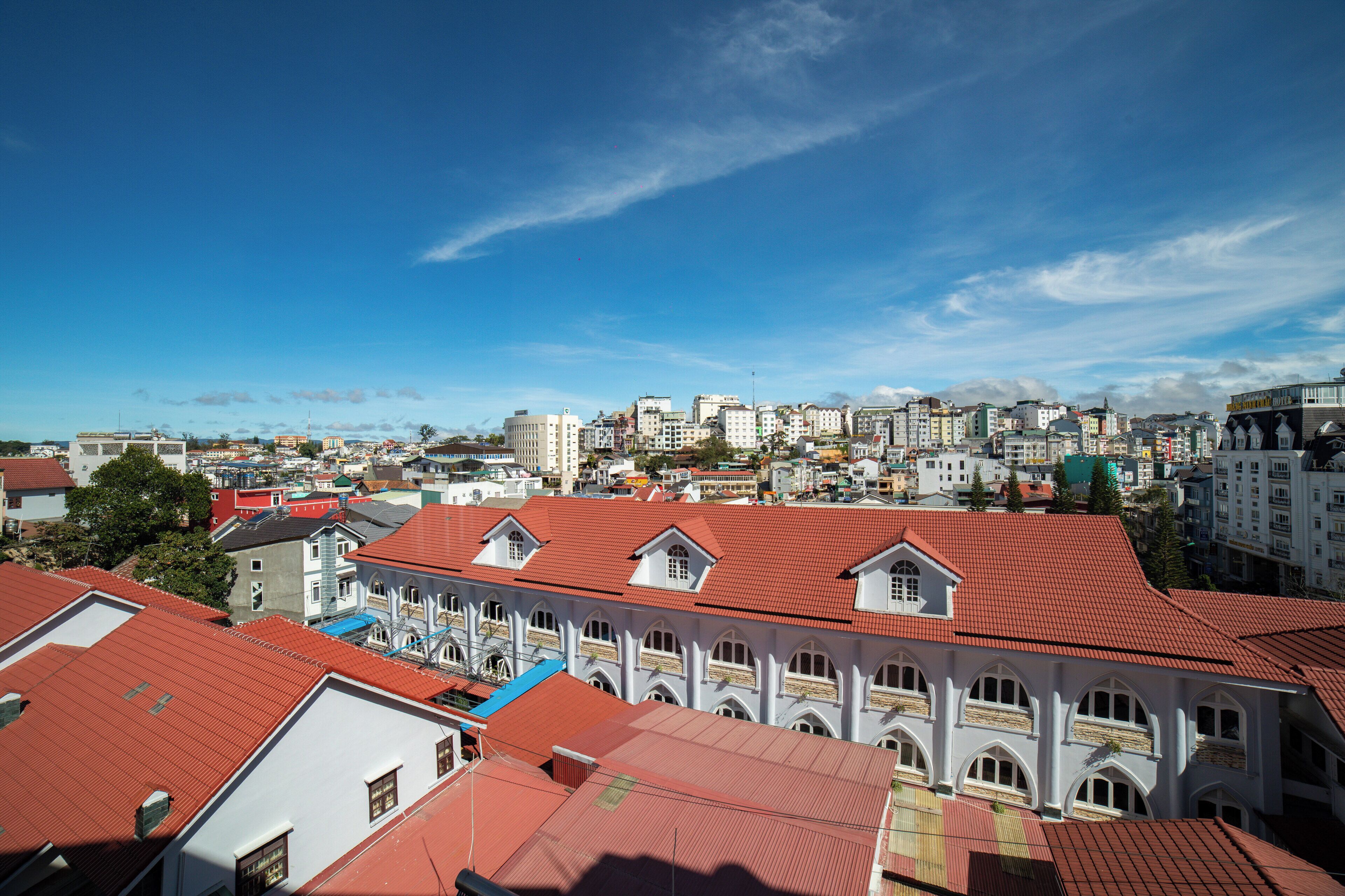 A cityscape with a prominent building featuring a red-tiled roof and arched windows.