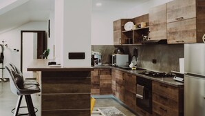 Uma cozinha moderna com armários de madeira, uma ilha central e um espaço de refeições com uma cadeira.
