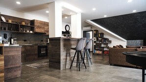 Cozinha moderna com armários de madeira escura, uma ilha central com banquetas e uma área de jantar com mesa redonda.