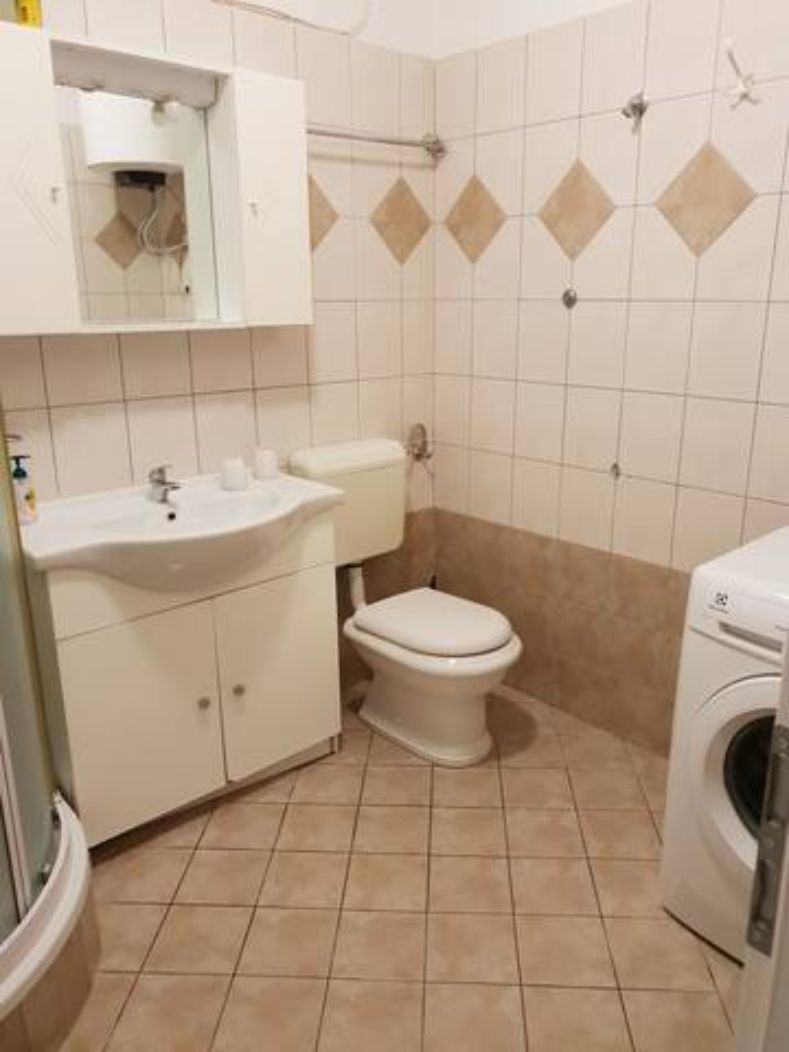 Un baño pequeño con inodoro, lavamanos y lavadora.