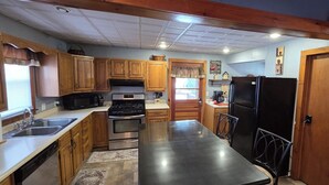 A kitchen with wooden cabinets, stainless steel appliances, a black refrigerator, and a central island. - Welcoming 3-bedroom house in charming Canton for your getaway (Canton)