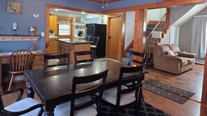 A dining area with a wooden table and chairs, a kitchen in the background, and a staircase leading to another level. - Welcoming 3-bedroom house in charming Canton for your getaway (Canton)