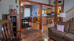 A spacious living room with a wooden dining area, a kitchen with wooden cabinets, and a staircase leading to another level. - Welcoming 3-bedroom house in charming Canton for your getaway (Canton)