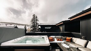 Ett bubbelbad och en utomhusplats med sittmöbler, med ett snötäckt landskap i bakgrunden.