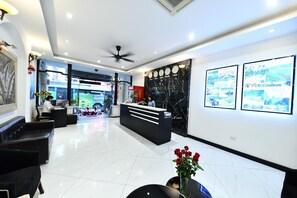 A hotel reception area with a modern design, featuring a reception desk, seating area, and a large wall with framed pictures. - Hanoi Blue Sky Hotel (Hanoi)