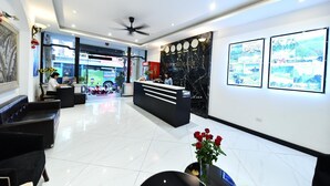 Een receptiegebied van een hotel met een modern design, met een receptiebalie, een zithoek en een grote muur met ingelijste foto's.