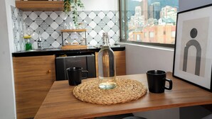 Une cuisine avec une table en bois, une bouteille transparente et deux tasses noires.