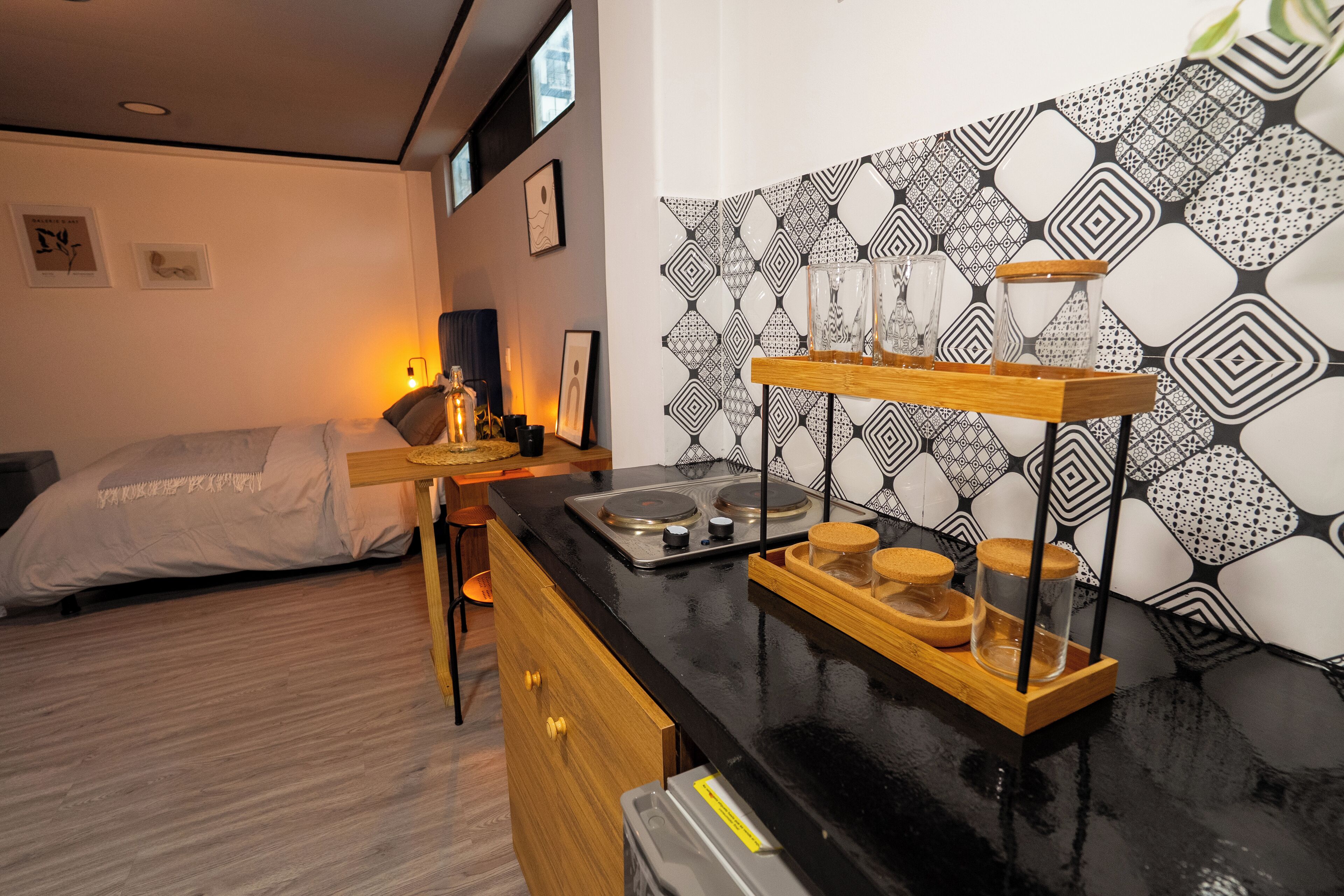 Une cuisine de taille réduite avec un plan de travail noir, des placards en bois et un pare-feu décoratif.