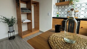 Une cuisine moderne avec une table en bois, un set de table en fibres naturelles, une bouteille transparente et une plante en pot.