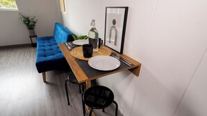 Un coin repas avec une table en bois, des chaises noires, un canapé bleu, une plante en pot et un tableau encadré au mur.