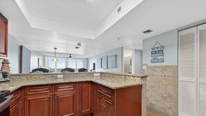 A spacious kitchen with granite countertops, wooden cabinets, and a large island. - Coastal Daydream At White Surf (Daytona Beach)