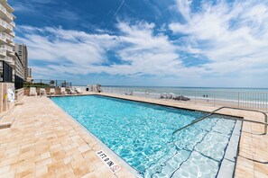 Ein Swimmingpool mit Tiefenhinweisschild von 90 Zentimetern, umgeben von einer gefliesten Terrasse und einem Geländer, mit Blick auf einen Strand und den Ozean.