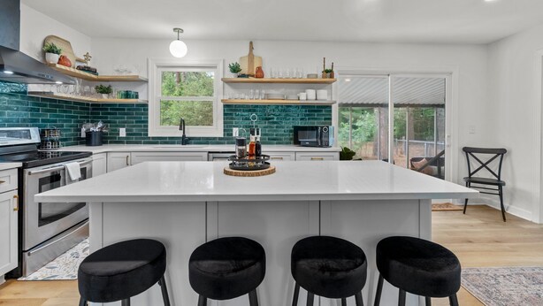A modern kitchen with a large island, white cabinetry, and green backsplash tiles. - The Charming Pines Hideaway - 3B/2B - Golfer's Paradise (Southern Pines)