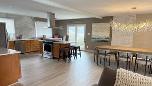 A modern kitchen with a central island, wooden cabinets, and a stainless steel dishwasher. - Spacious 4-bedroom Ranch Cape May Oasis Master Spa Hot Tub (Cape may)