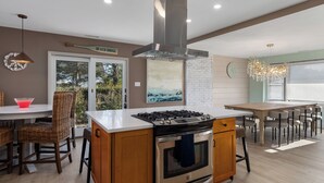 A modern kitchen with a central island, stainless steel appliances, and a dining area with a view. - Spacious 4-bedroom Ranch Cape May Oasis Master Spa Hot Tub (Cape may)