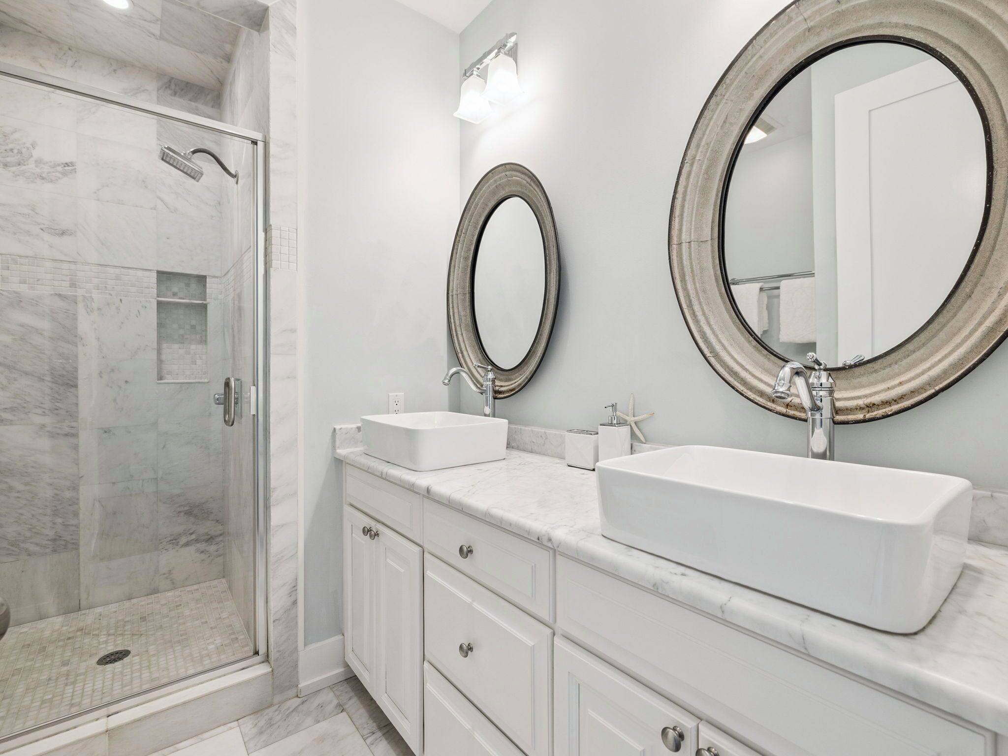 A bathroom with a walk-in shower, two sinks, and two large mirrors.