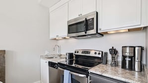 Una cocina moderna con electrodomésticos de acero inoxidable, armarios blancos y encimera de granito.