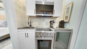 Una cocina moderna con armarios blancos, una estufa de acero inoxidable y un horno empotrado.