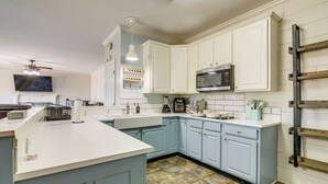 A kitchen with white and light blue cabinets, a central island, a microwave, and a coffee maker.