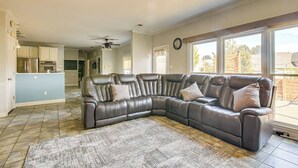 A spacious living room with a large L-shaped leather sofa, a patterned rug, and a ceiling fan.