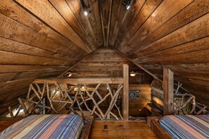 A cozy attic bedroom with wooden walls and sloped ceilings, featuring two beds and a rustic wooden ladder. - Four Seasons Mountain Escape - Riverfront | Pet Friendly | Hot Tub (Blue Ridge)