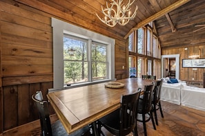 A wooden interior with a dining table, chairs, and a chandelier. - Four Seasons Mountain Escape - Riverfront | Pet Friendly | Hot Tub (Blue Ridge)