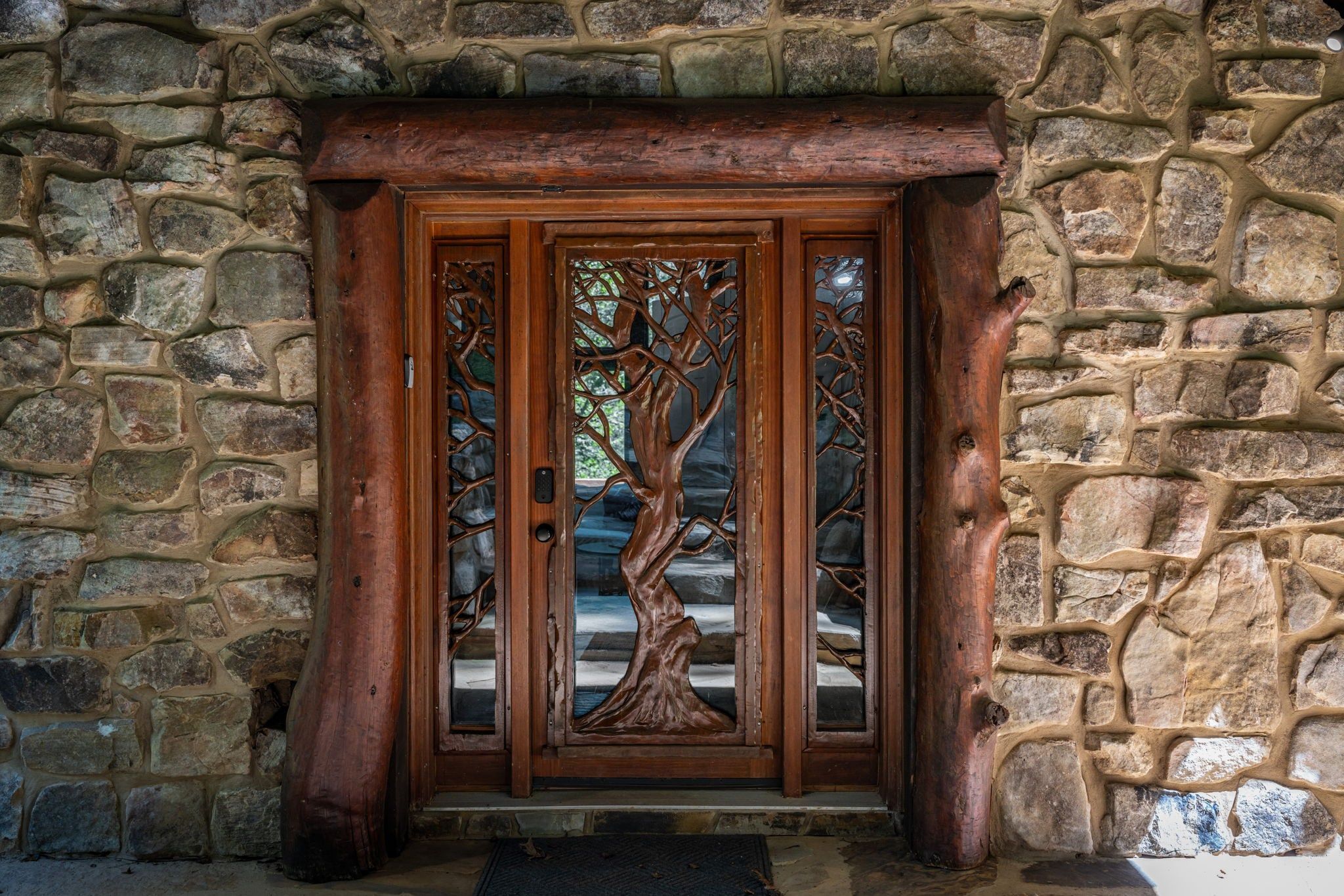 Uma porta de madeira com um entalhe de árvore, embutida em uma parede de pedra.