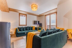 A modern living room with a sectional sofa, a flat-screen TV, and large windows. - Sensational 3 bedroom, 3 bathroom, central locatin (Vaujany)