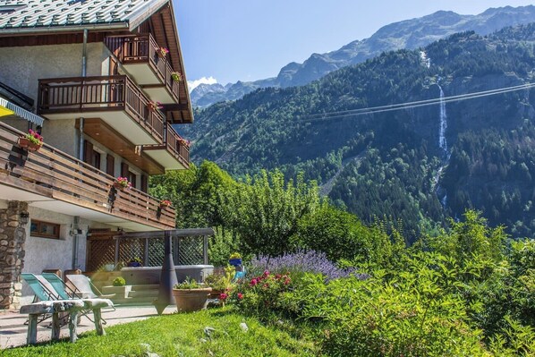 Eine Berghütte mit Balkon mit Blick auf ein bewaldetes Tal und einen Wasserfall.