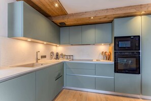 Eine moderne Küche mit Einbauofen, Spüle und Holzbalkendecke.
