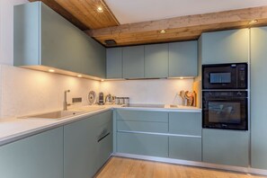 Eine moderne Küche mit hellblauen Schränken, einer Holzbalkendecke und integrierten Geräten.