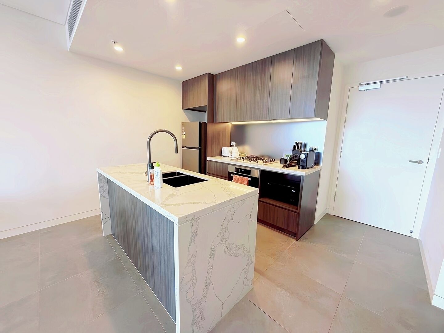 Een moderne keuken met een marmeren eiland, roestvrijstalen apparatuur en houten keukenkastjes.