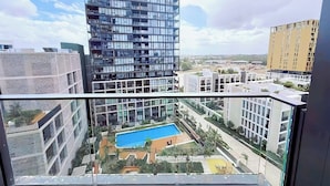 Un grattacielo con una moderna facciata in vetro, una piscina sul tetto e edifici residenziali circostanti.